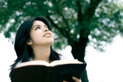Young woman with Bible, looking up to God