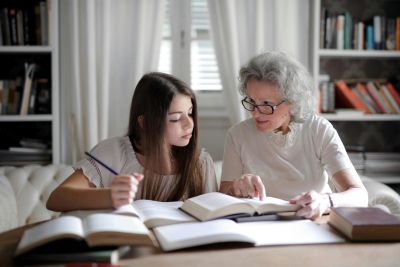 An old lady, with wise eyes, teaching a young girl, who seems eager to learn